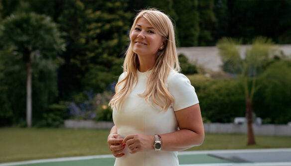 Movik Gabriella ingatlanközvetítő, az Ingatlan Coach iroda alapítója egy fehér ruhában, a háttérben zöld fű és fák látszanak.