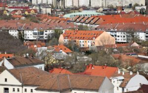 Városi kilátás: sűrűn beépített terület különböző színű és formájú háztetői.